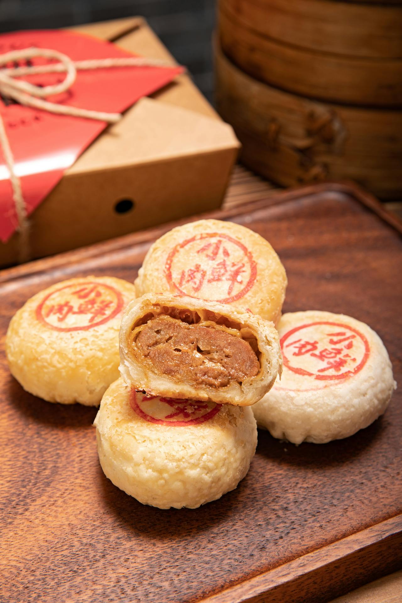 Gros plan sur des Mooncakes traditionnels chinois à pâte feuilletée fourrés à la pâte d'haricot rouge, coupés pour révéler la garniture. Posés sur un plateau en bois, cette image met en valeur des accords thé mooncake pour les thés comme thé vert et fleurs d'osmanthus.