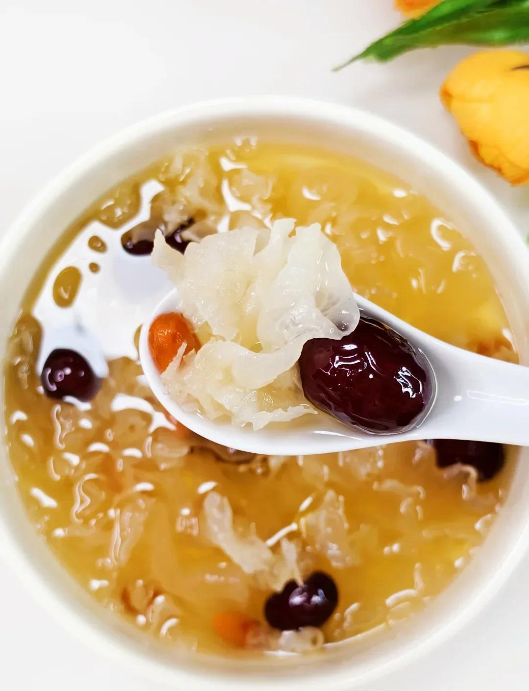 Gros plan sur un bol de dessert ou d'infusion chinoise à la trémelle blanche (Yin Er), avec des dattes jujube et baies de goji, servi dans une cuillère, illustrant les bienfaits d'une plante chinoise hydratante pour la santé.