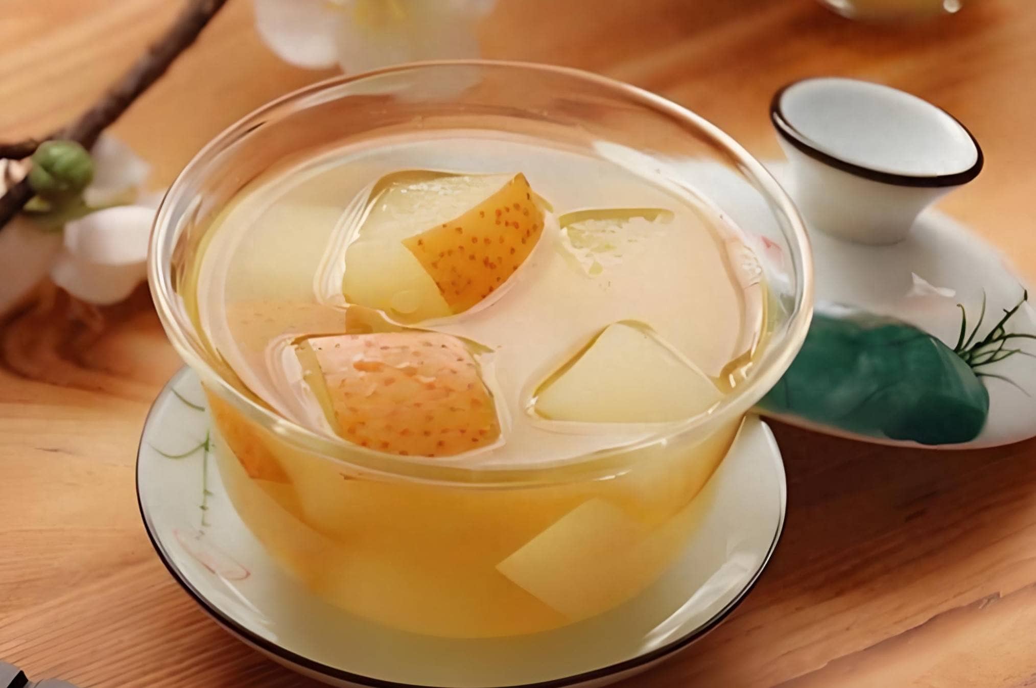Bol de tisane chinoise à la poire avec morceaux de fruits, boisson chaude traditionnelle posée sur une table en bois.