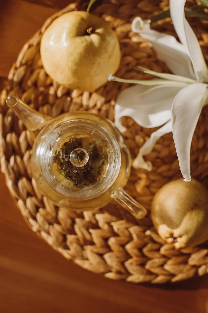 Bol de tisane chinoise à la poire avec morceaux de fruits, boisson chaude traditionnelle posée sur une table en bois.