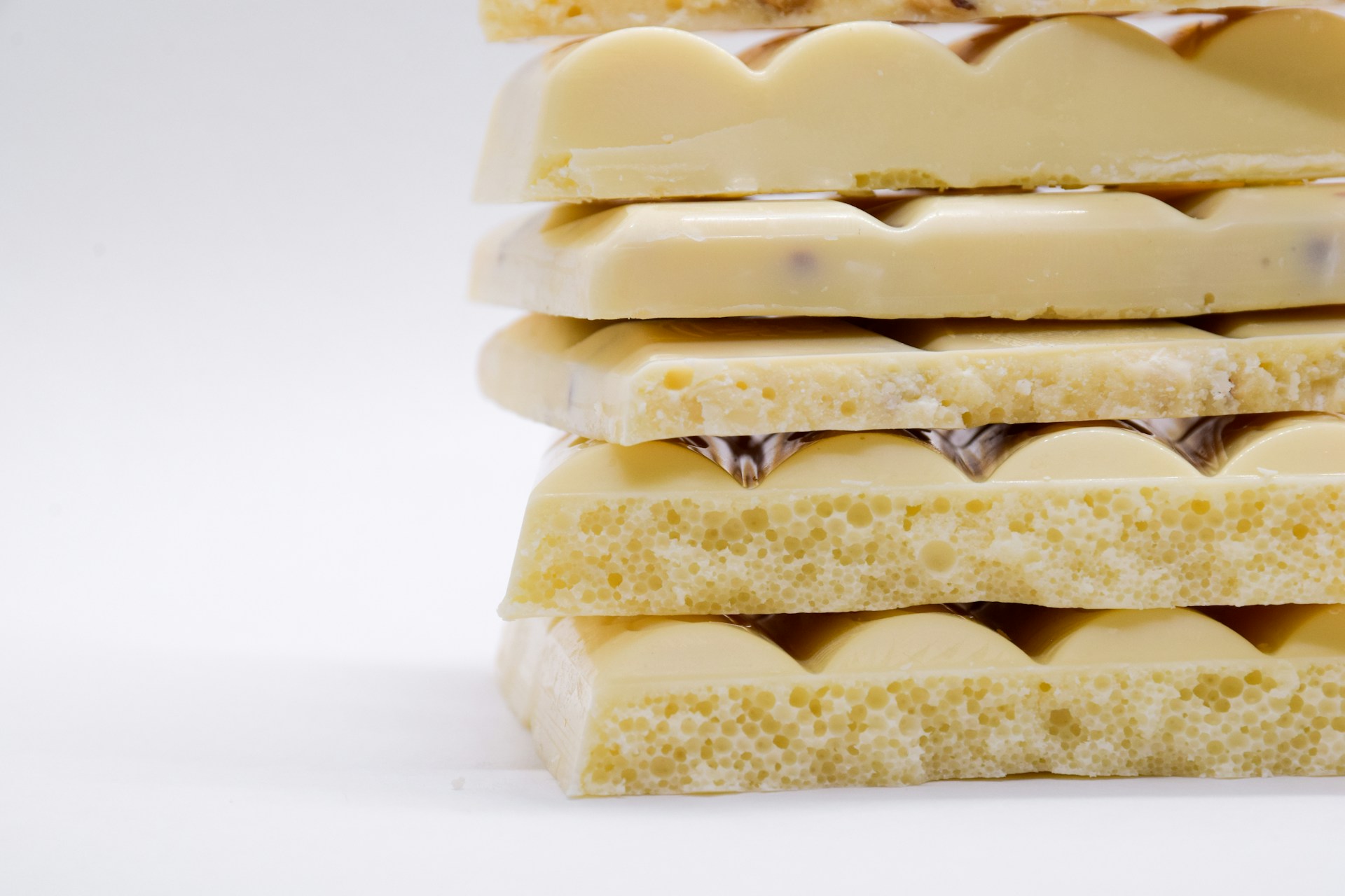 Tablettes de chocolat blanc cassées en morceaux sur un fond clair. L'image met en valeur le côté crémeux et sucré du chocolat, idéal pour un accord thé matcha ou thé vert genmaïcha.