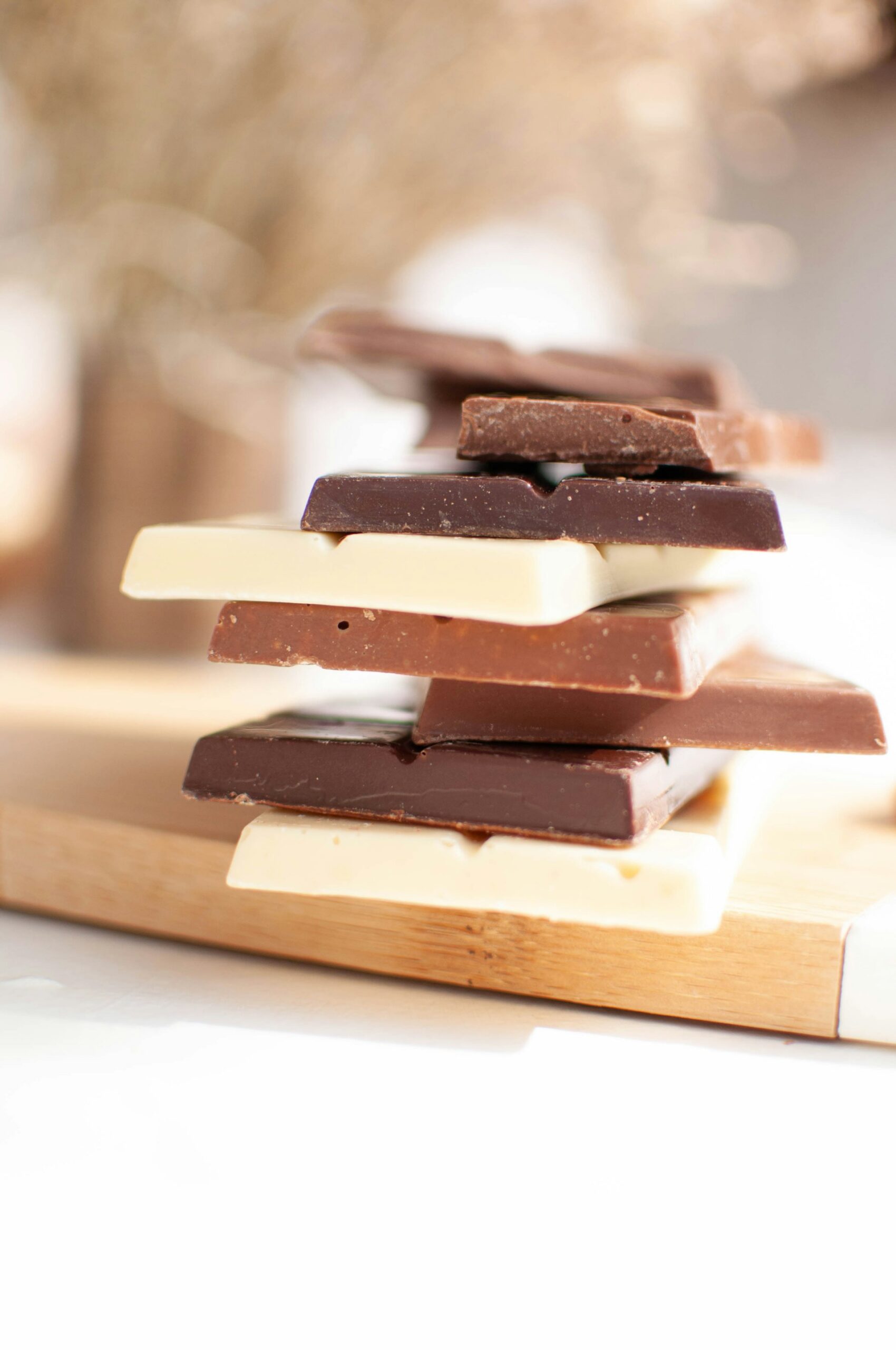 Tablettes de chocolat noir, de chocolat au lait et de chocolat blanc alignées pour la dégustation. L'image est une comparaison des trois saveurs, idéale pour choisir le meilleur accord thé pour chaque type de chocolat.