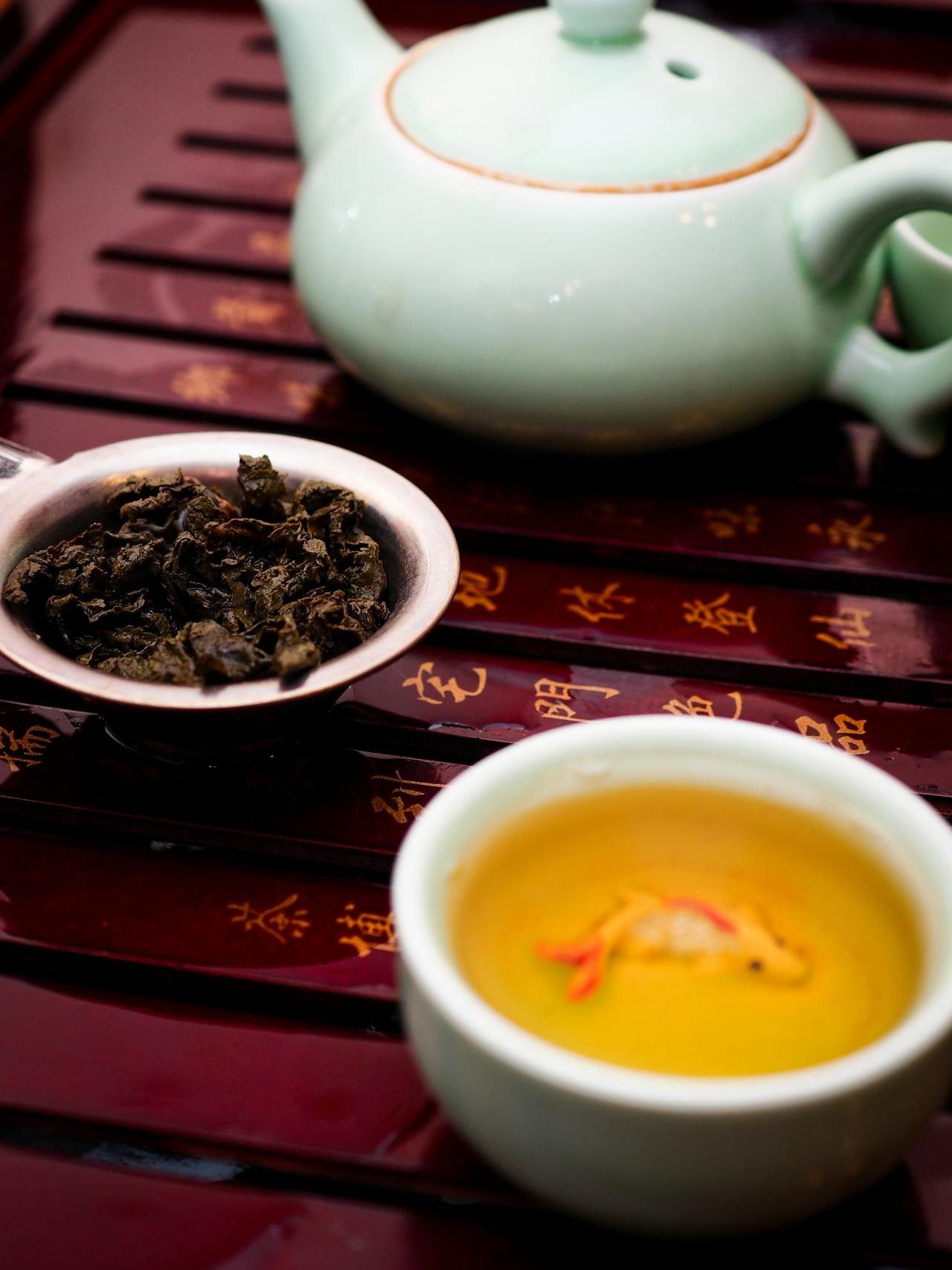 Une tasse de thé Oolong traditionnel avec un motif de poisson rouge, reconnu comme le meilleur thé pour la digestion en France, servi avec une théière artisanale.