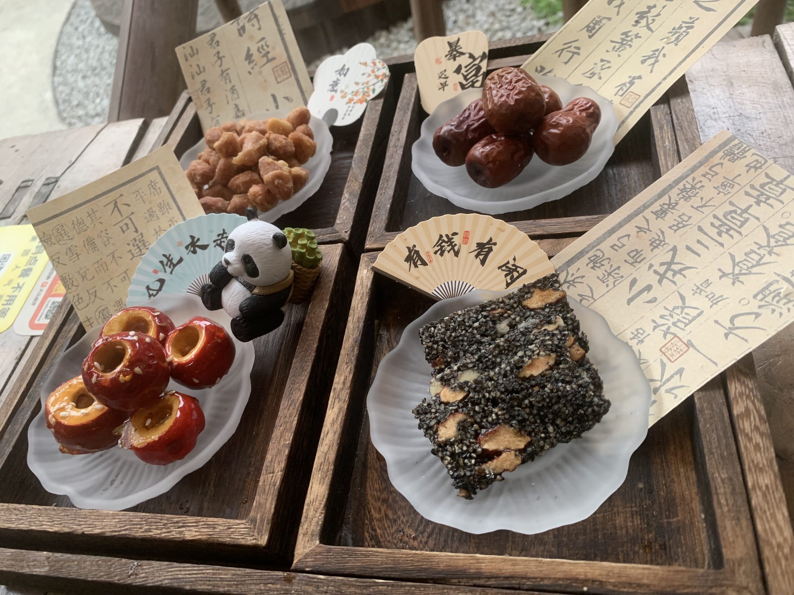 Mascotte de thé panda (tea pet) sur un plateau de dégustation traditionnel à Chengdu avec des douceurs chinoises.