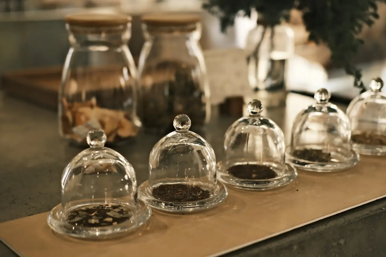 Séance olfactive de dégustation du thé avec quatre cloches en verre abritant différents types de thé sec pour humer leur bouquet, une étape clé pour développer son vocabulaire du thé, apprendre comment décrire un thé et identifier son profil aromatique du thé avant l'infusion, afin de rédiger des notes de dégustation précises.