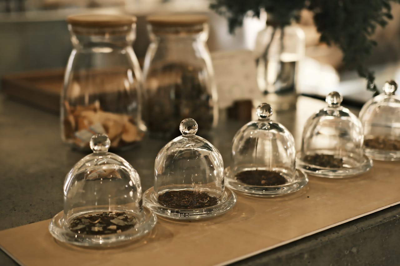 Séance olfactive de dégustation du thé avec quatre cloches en verre abritant différents types de thé sec pour humer leur bouquet, une étape clé pour développer son vocabulaire du thé, apprendre comment décrire un thé et identifier son profil aromatique du thé avant l'infusion, afin de rédiger des notes de dégustation précises.