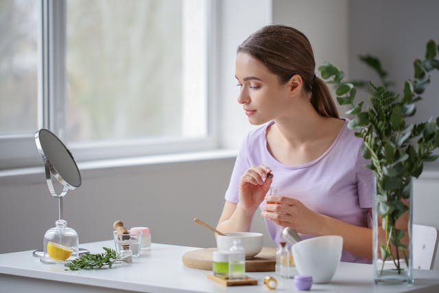 Jeune femme préparant un soin cosmétique maison pour profiter des bienfaits du thé sur la peau, utilisant notamment du thé vert contre l'acné afin d'obtenir un teint éclatant et lumineux.