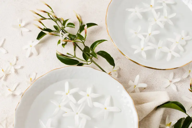 Fleurs de jasmin fraîches flottant dans des coupelles d'eau, illustrant la question "Quel goût a vraiment un bon thé au jasmin chinois ?
