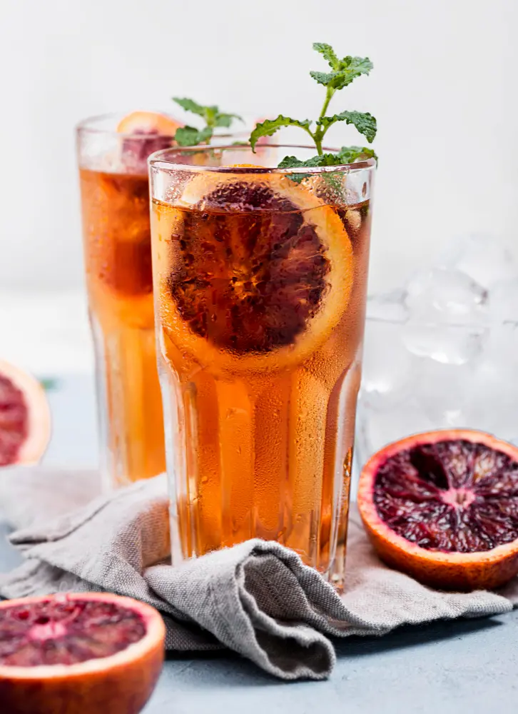 Deux grands verres de thé earl grey glacé au pamplemousse et à la menthe, une excellente idée de boisson parmi les meilleurs thés fruités pour l'été.