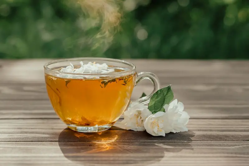 Voici une proposition de texte alternatif pour l'image pexels-filirovska-7138780.webp :
« Une tasse de thé au jasmin fumante sur une table en bois, accompagnée de fleurs de jasmin fraîches, illustrant la question "Comment reconnaître un bon thé au jasmin