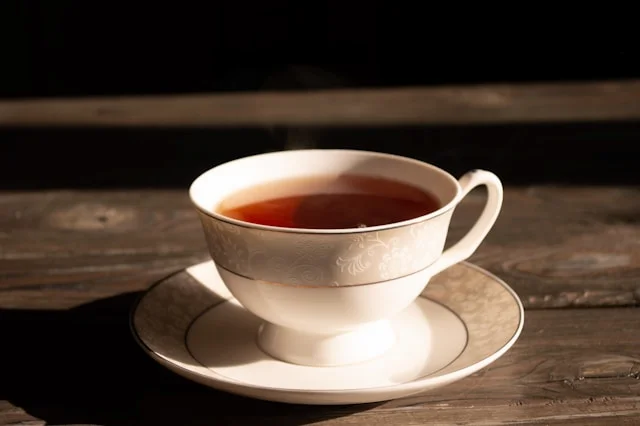 Tasse en porcelaine blanche contenant du thé noir, posée sur une table en bois et illustrant pourquoi mon thé est amer