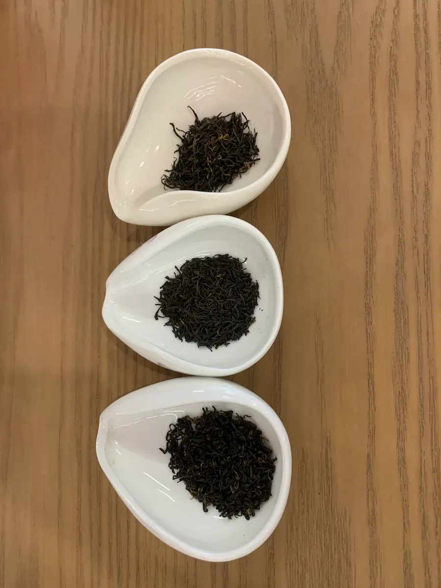 Trois coupelles de présentation montrant la finesse des grades de feuilles sèches de thé keemun noir lors d'un voyage à Qimen.