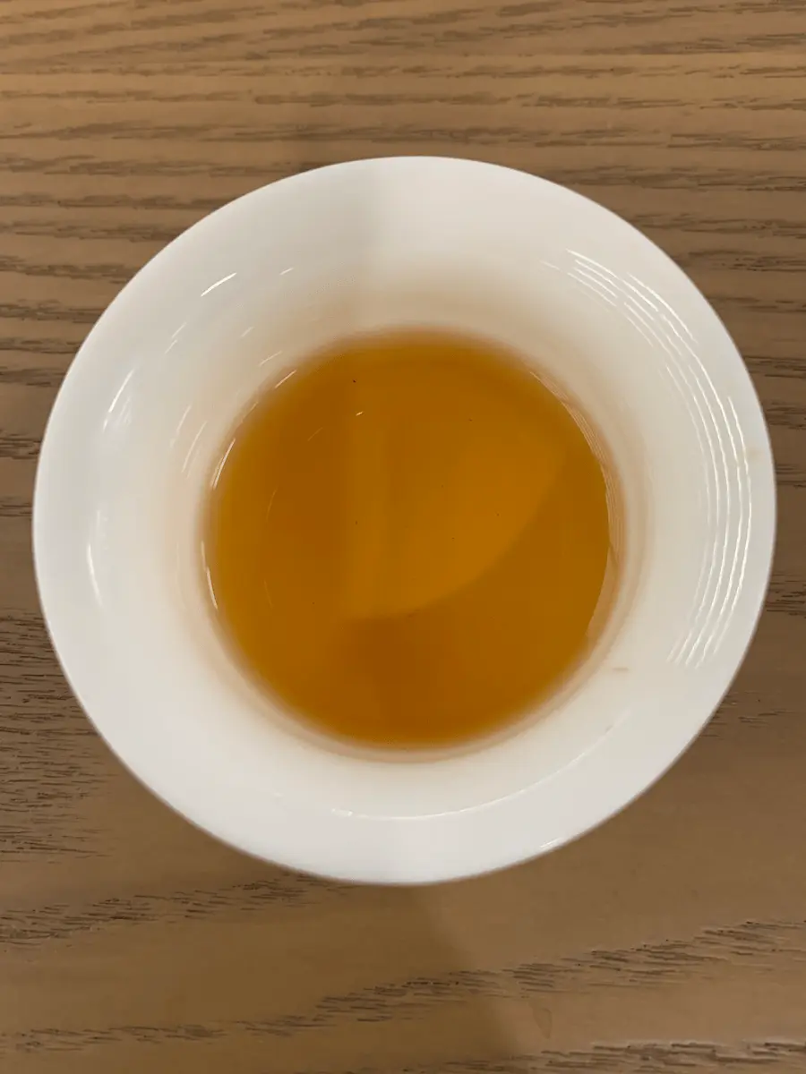 Tasse en porcelaine dévoilant une liqueur de thé keemun couleur ambre foncé lors d'un voyage à Qimen.