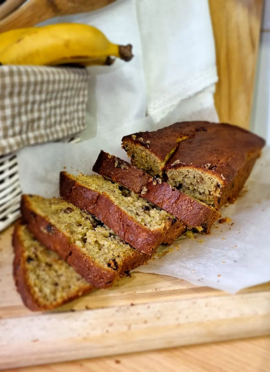 Tranches de banana bread moelleux servies sur une planche en bois, parfait pour une pause thé et dessert d'automne réconfortante cet automne.